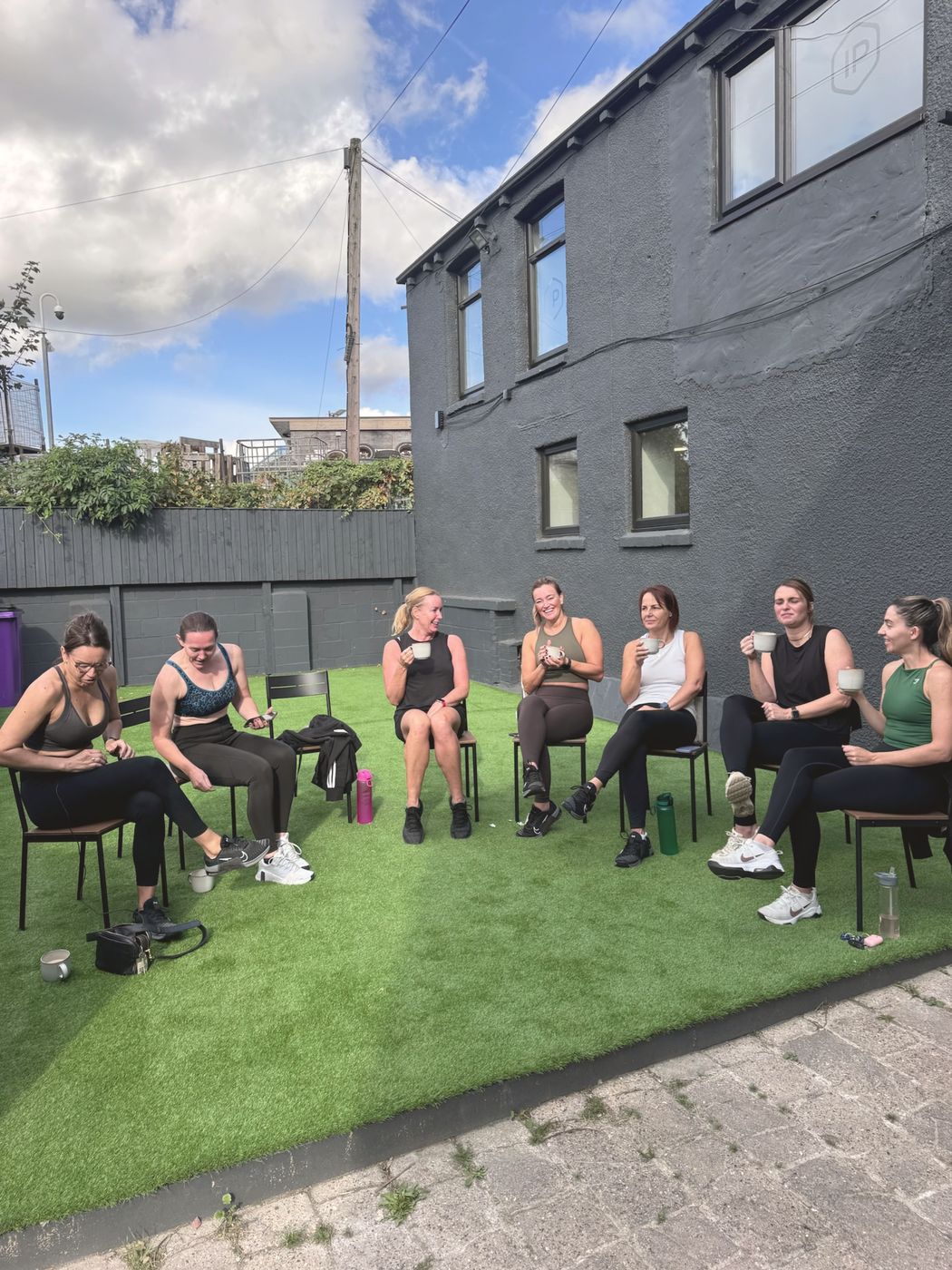 Members sitting together in a circle on the grass outside the studio